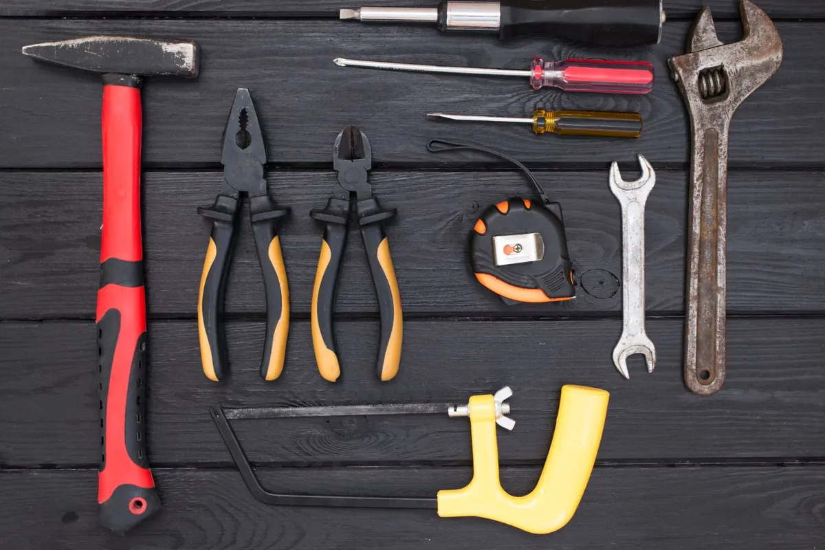 Handyman hand tools laid out neatly on a workbench: hammer, pliers, screwdrivers and wrenches