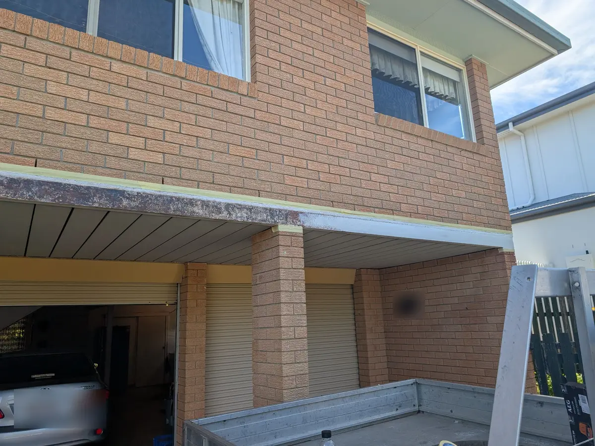 Before: rusted, flaking carport beam above a garage, masked off ready for rust treatment